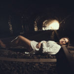 Chica en el túnel abandonado acostada en las vías