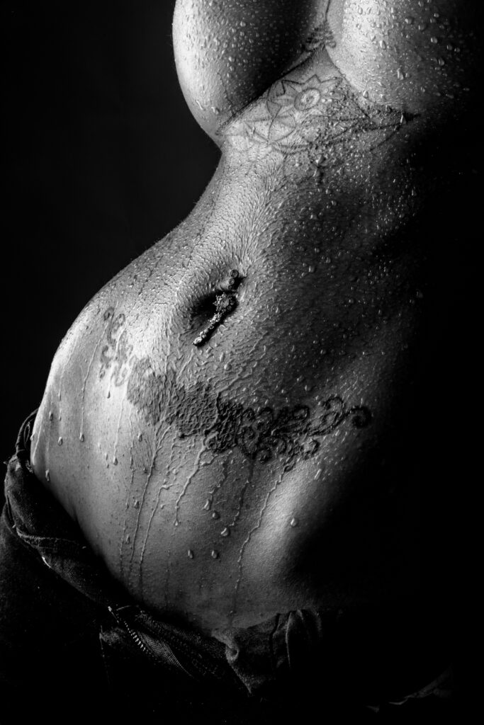 Vaqueros, tatuajes, piercings y gotas de agua en el cuerpo